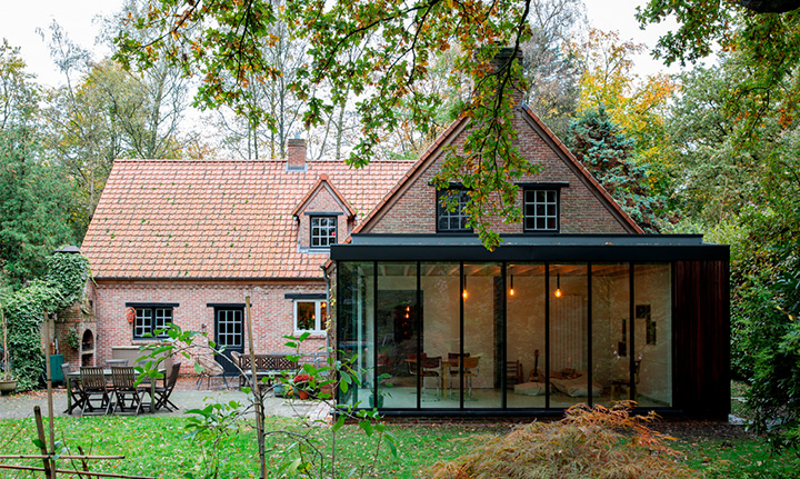 Landelijke woning met een nieuwe aanbouw in hout en glas, op een groen perceel